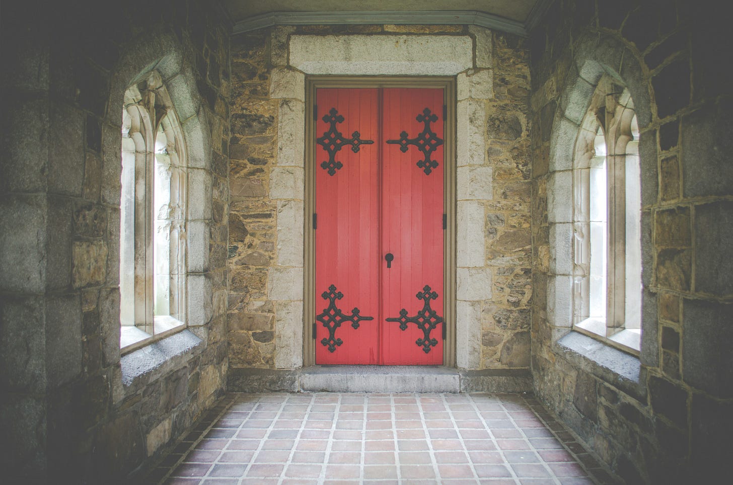 Red doors, closed, in a stone hall