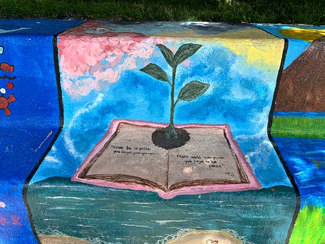 sections of the painted bench: Winnie the Pooh and friends, a rainbow, a book with a flower growing out of it.