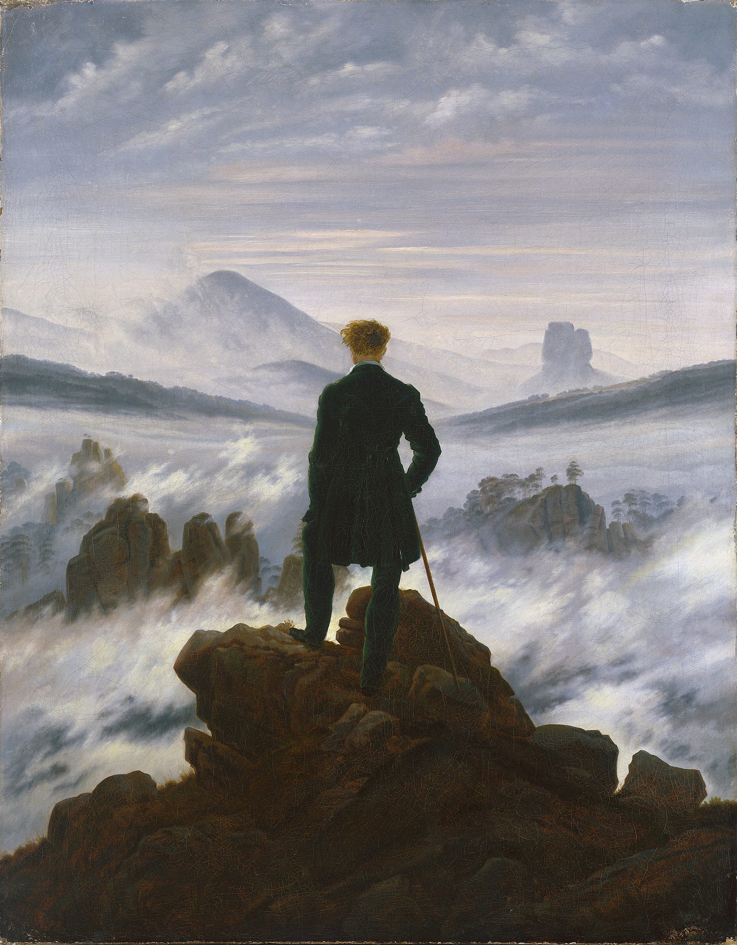 Man in early 19th century dress, seen from behind, on rocky hilltop above a sea of mist