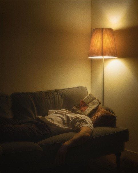This may contain: a person laying on a couch under a lamp