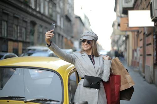 Free Woman in Gray Coat Holding Black Smartphone Stock Photo