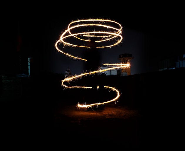 Image of a silhouette of a person with lights spiralling around them. Image of a silhouette of a person with lights spiralling around them.
