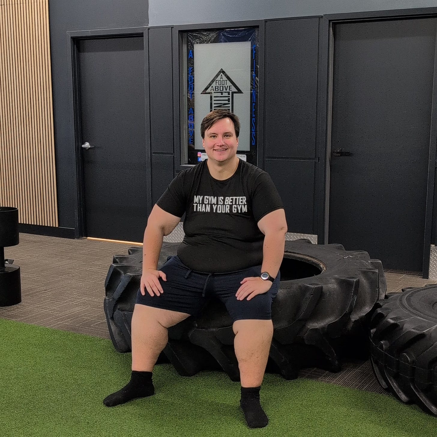 Gabriel sitting on a tire at A Foot Above Fitness