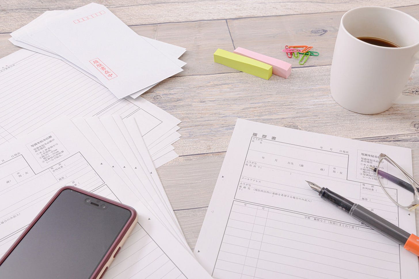 デスクの上に散らばった書類とコーヒーカップ、スマートフォン