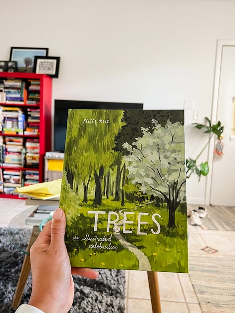 Photo of a hand holding up an illustrated book entitled 'Trees,' in a living room with a red bookcase and a tv in the background; mirror selfie photo of woman in a short dress and cap and carrying a bag; photo of a tree with several orchids of different colors along a sidewalk in front of a building; photo of a coastline with water in the background and a city skyline in the distant background, with a towering art sculpture and palm trees in the foreground; a photo of a woman's legs and painted toes sitting on green grass with a backpack on her left and a rocky shore and water from a bay in front of her; photo of a white stone archway with ivory and patterned tiles inset, and palm leaves on the ground below, with patches of light and shadow against the wall; a convertible car with paintings and the words 'Everybody LOVE everybody' and bumper stickers that say things like 'Life Without Art is Stupid'; a photo of a head-on view of a baby blue with yellow trim lifeguard station on the sand with the ocean behind it; an overhead photo of a stack of magazines, scissors, and magazine clippings for a collage, on top of a clear glass coffee table and tile floor and rugs.