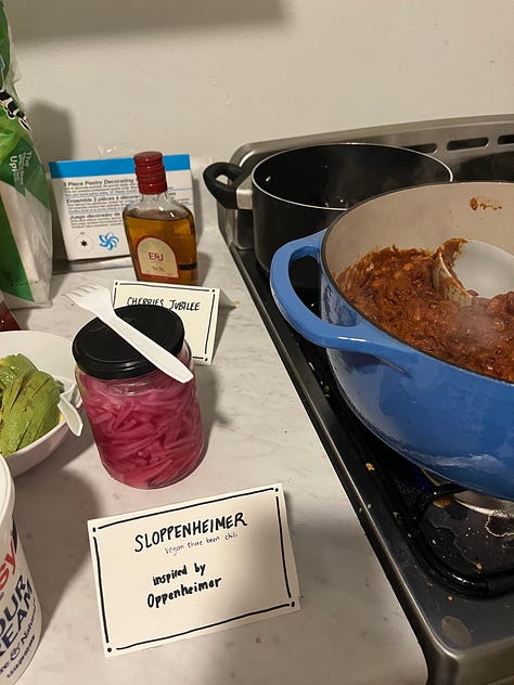 A dutch oven full of chili beside the label "Sloppenheimer," a stromboli behind a sign reading "Maestromboli," a plate of Almond Joys labeled "Da'Vine Almond Joy Randolph."