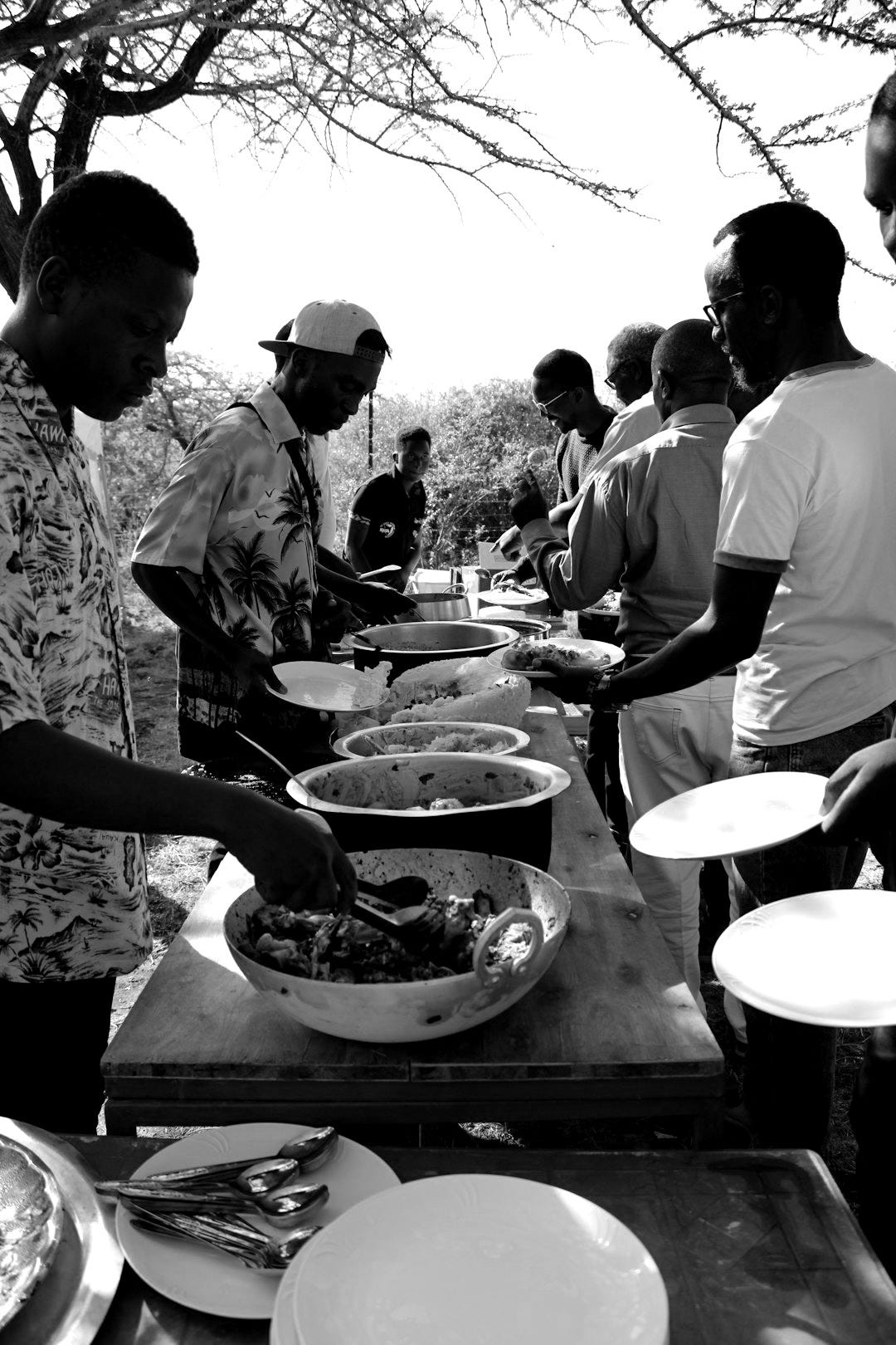 a group of people standing around a table filled with food