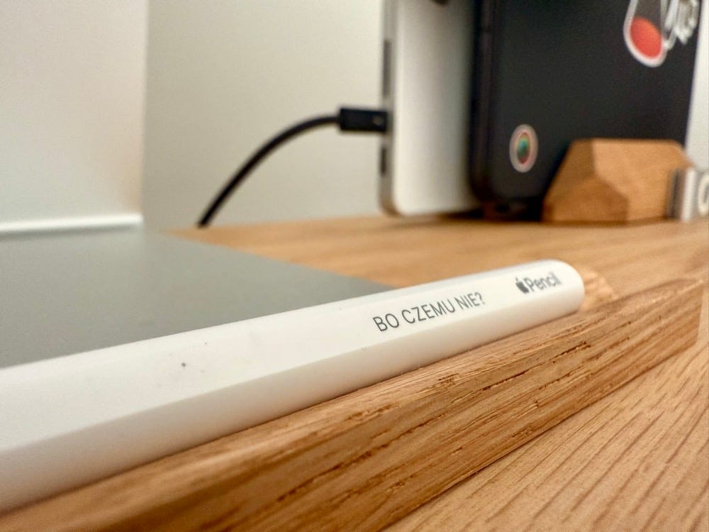 Zdjęcie Apple Pencil z napisem „Bo czemu nie?” w drewnianej, dębowej rynience.