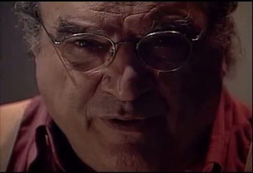 rosto em close do abujamra, com óculos ovais e pequenos, calvo e de nariz grande