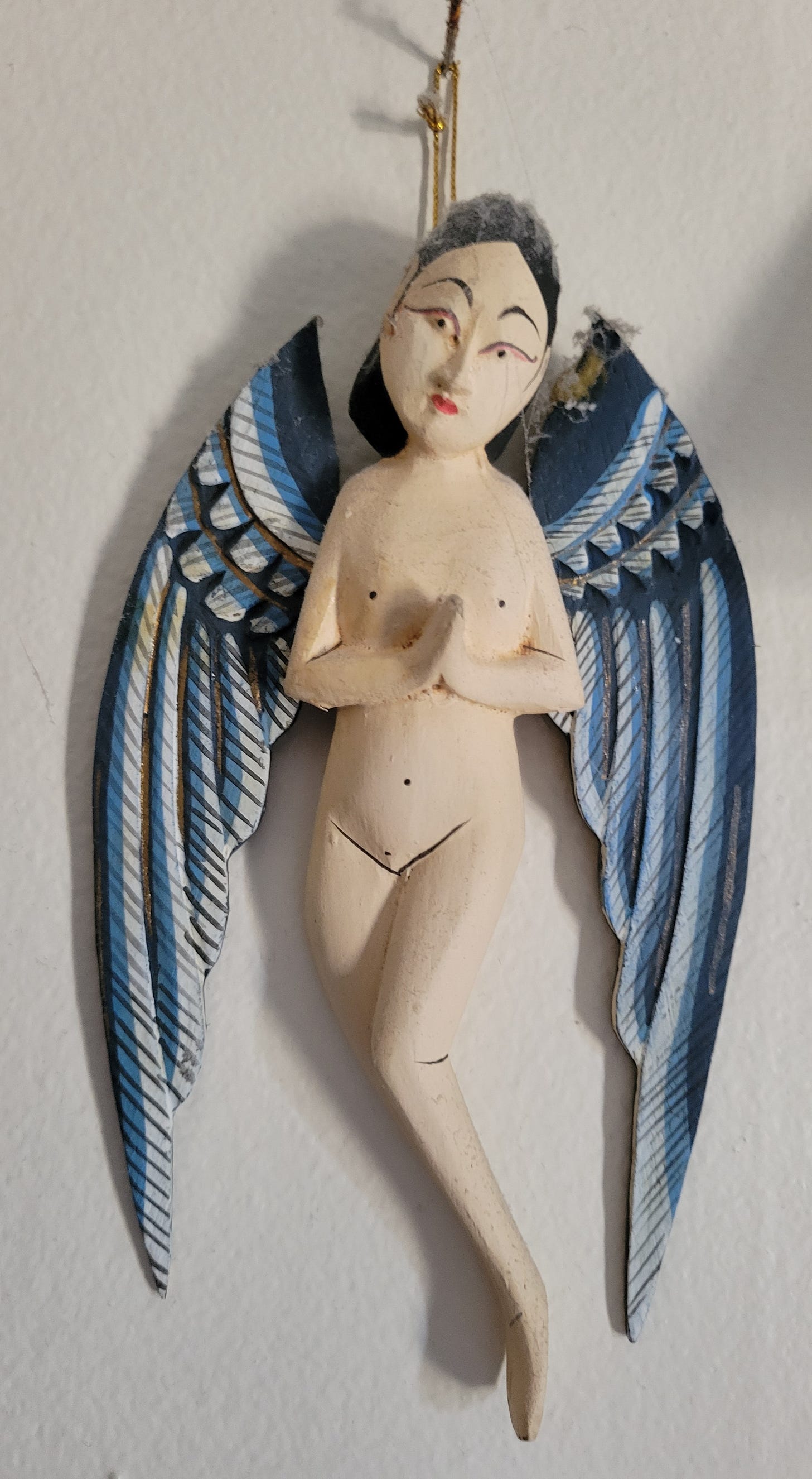 A wooden Balinese Angel hanging on a wall