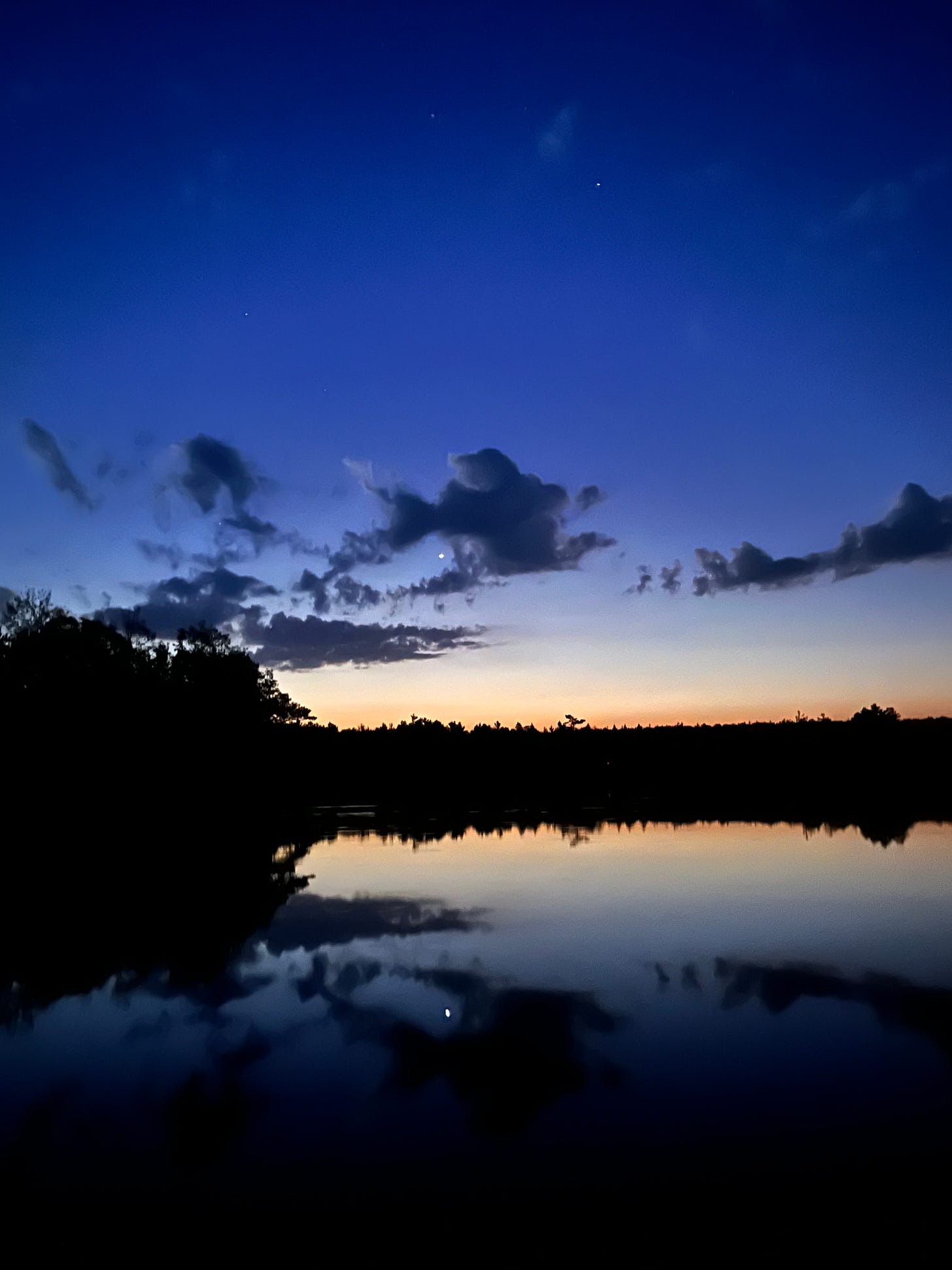 An indigo sky, pre-dawn with faint stars and a bright planet, above a lake