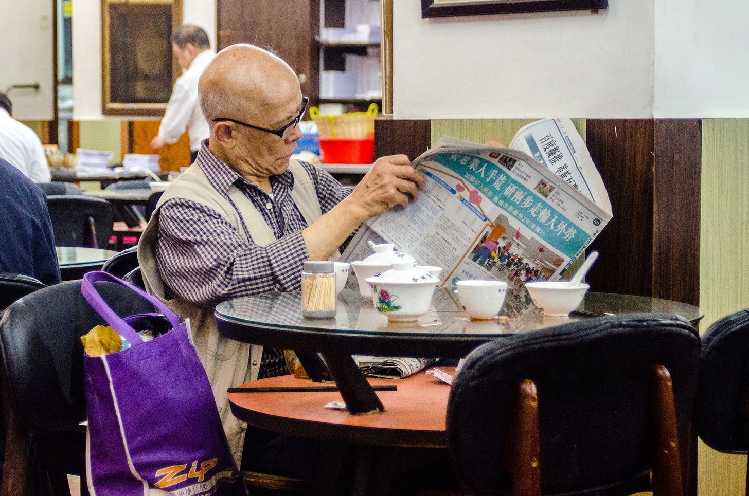 ID: Man at dim sum house reading newspaper ID: Man at dim sum house reading newspaper