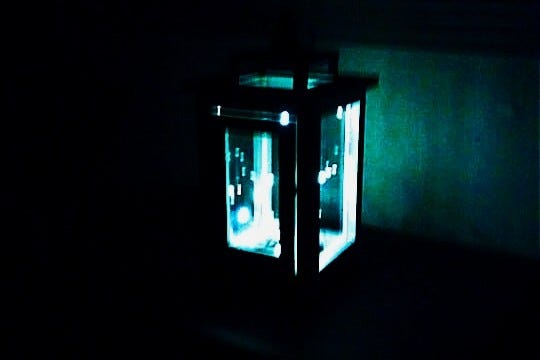 A lantern in the dark, casting light the color of the ocean