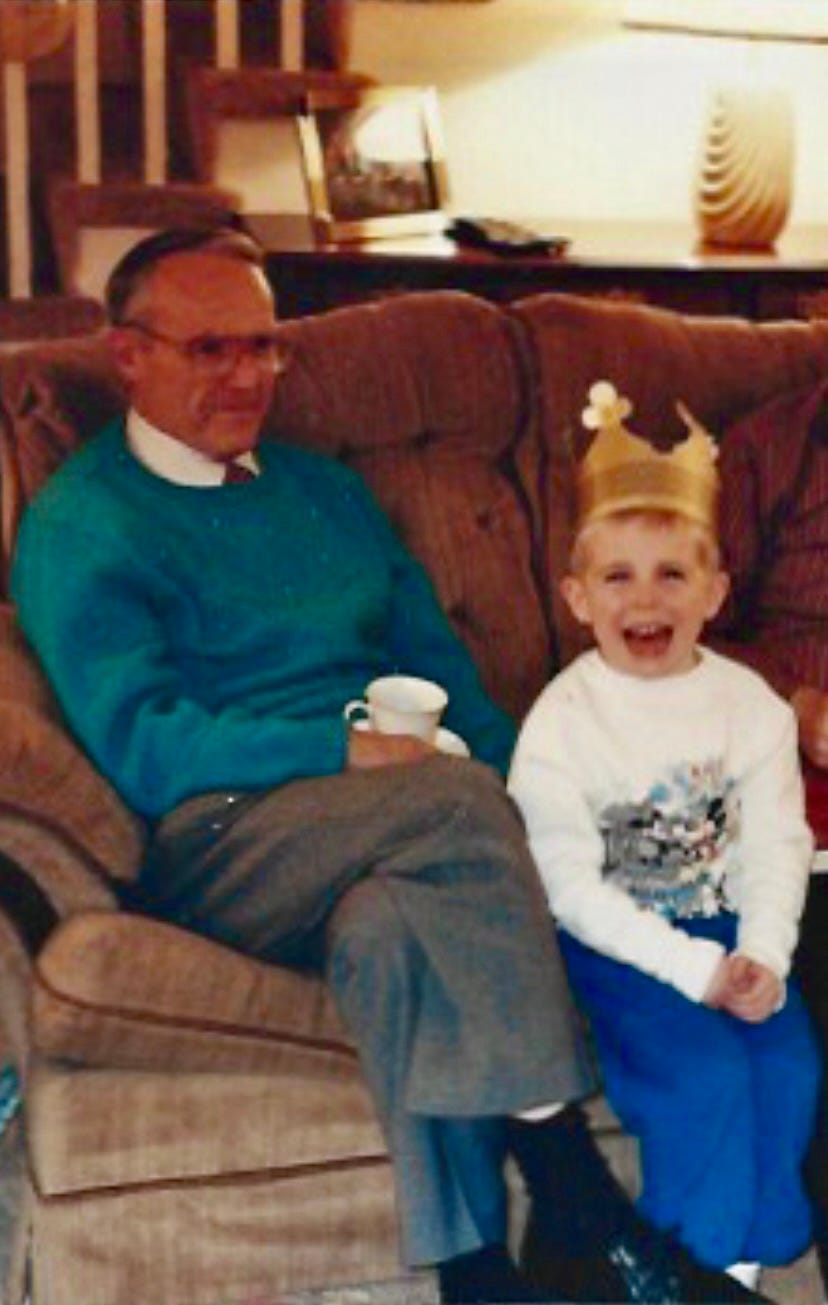 An old man and a young boy sit on a couch