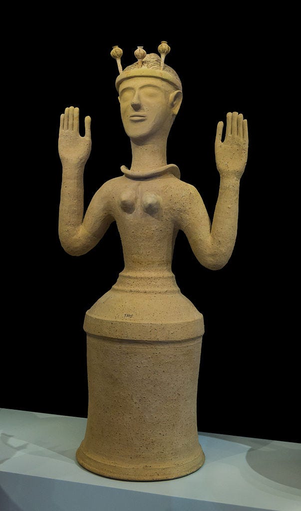 Ceramic female figurine with a flowerpot-shaped skirt, bare breasts, a necklace, and slightly schematized facial features. Her arms are held out to her sides with her hands raised, palms facing forward. Her hair is up in a tight bun and she wears a headband surmounted by three upright poppy pods.