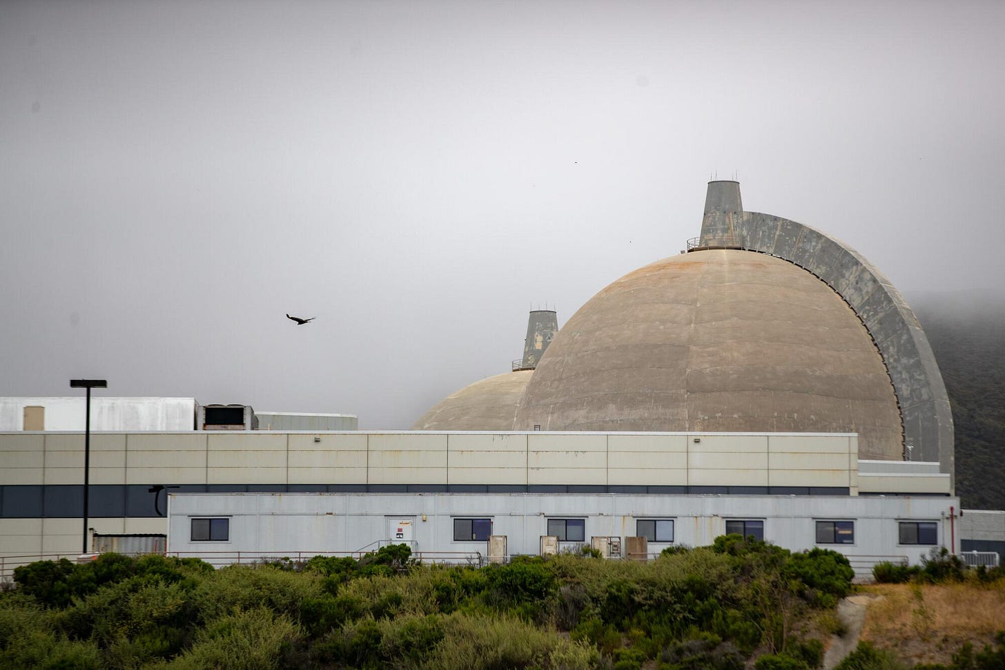 Two domed nuclear reactors can be seen along a coastline. Two domed nuclear reactors can be seen along a coastline.