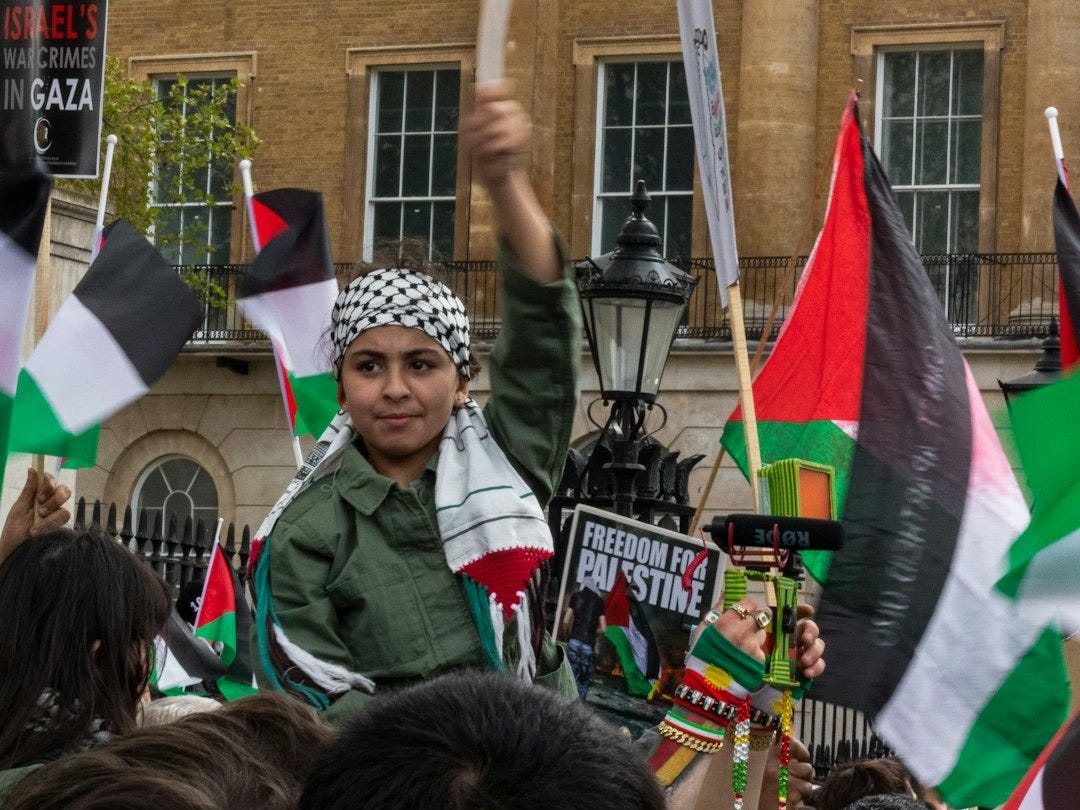 man in green jacket holding flag of us a during daytime