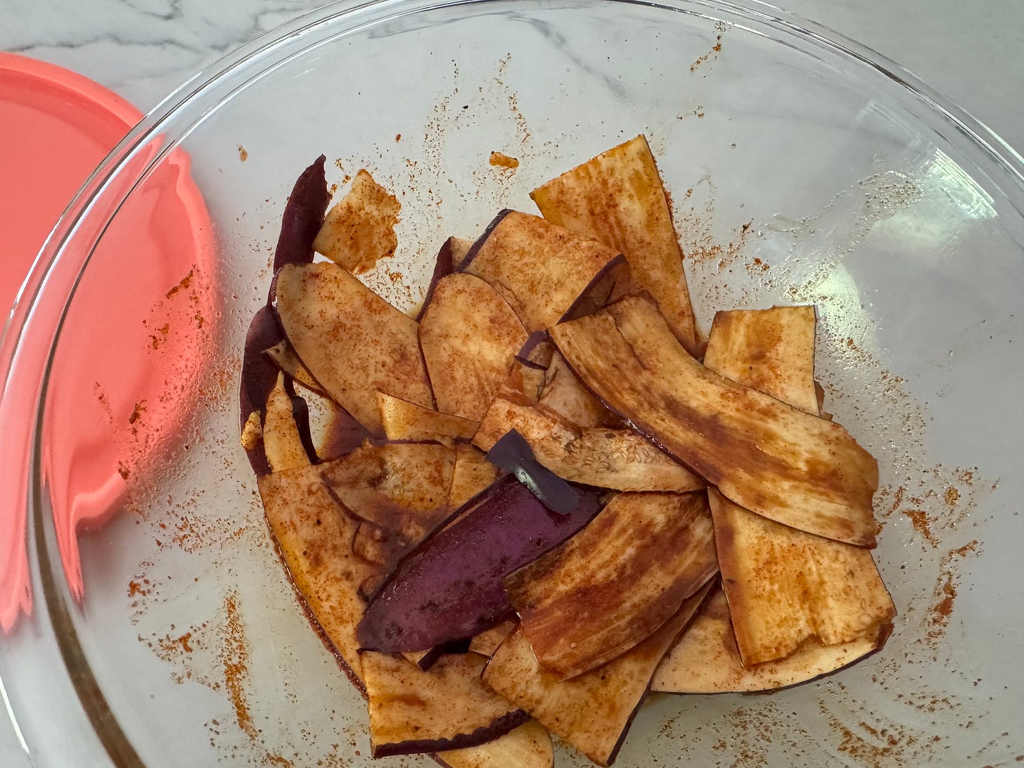 thin eggplant slices in a bowl of marinade