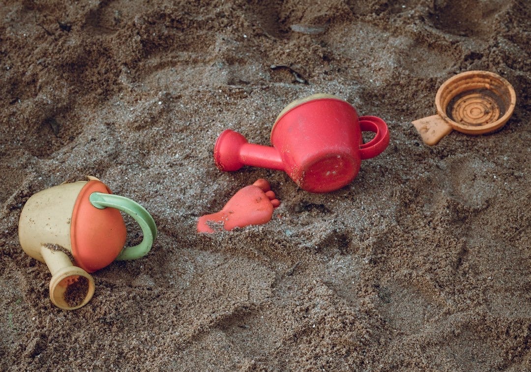 two yellow and red plastic watering cans on seashore two yellow and red plastic watering cans on seashore