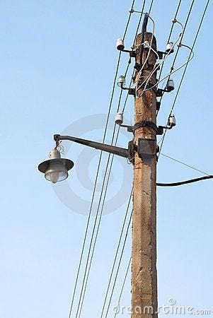 This may contain: an old telephone pole with power lines and street lights This may contain: an old telephone pole with power lines and street lights