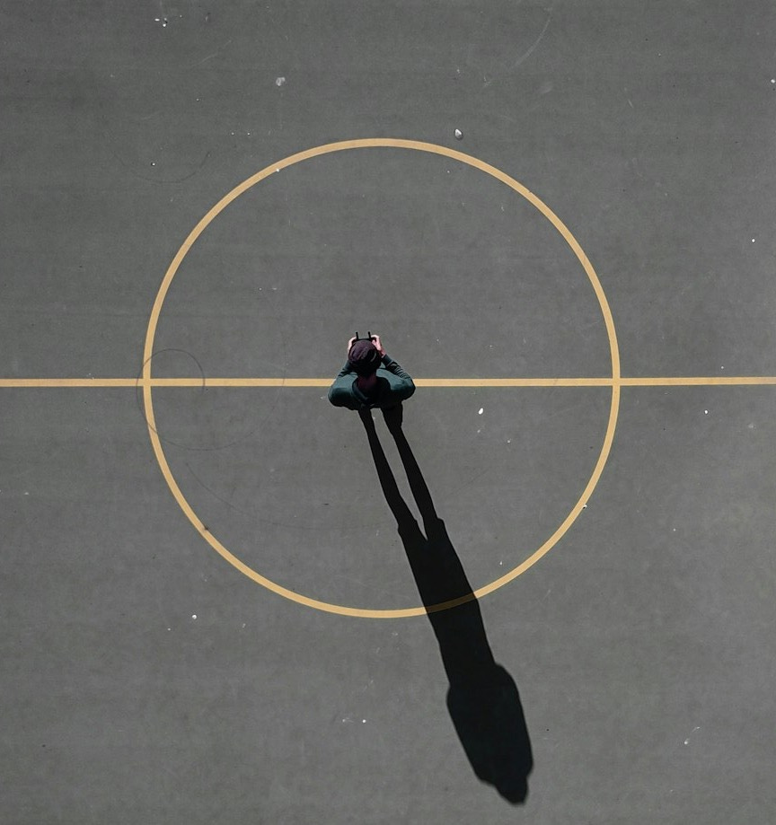 man stainding on black concrete floor casting shadow