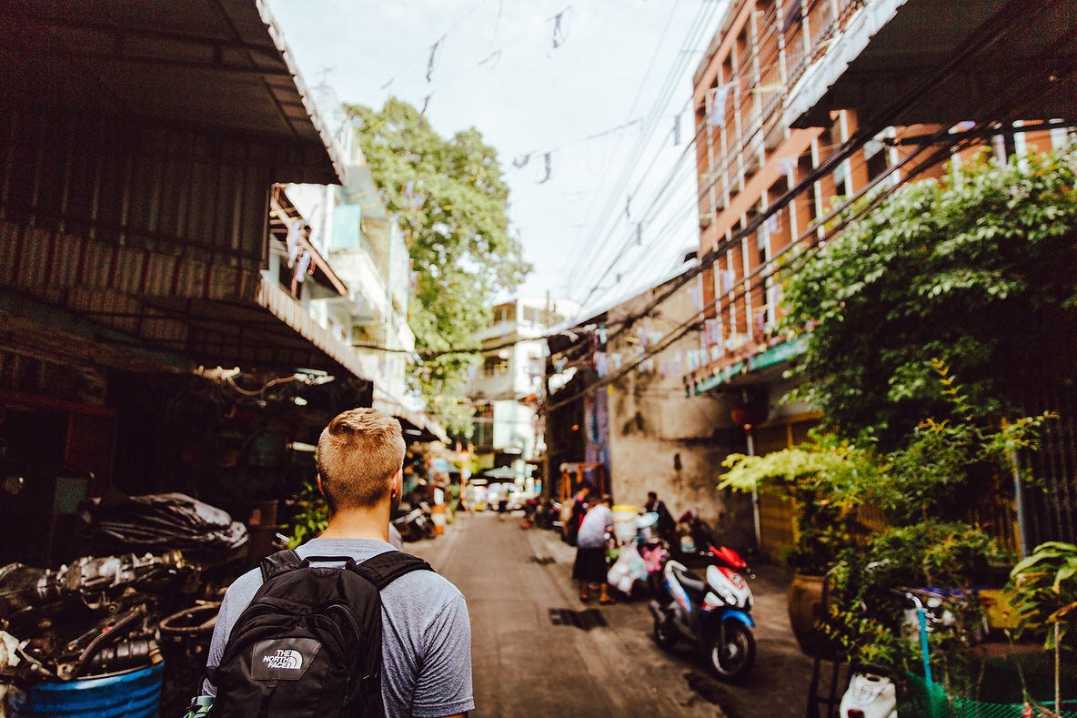 A backpacker walks down a busy side street in Bangkok.