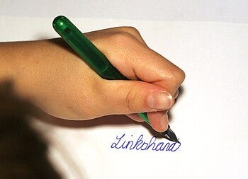 Left hand writing the German word "Linksh...