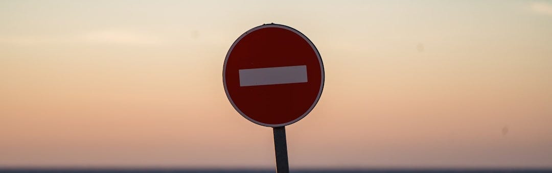 a red street sign sitting on the side of a road a red street sign sitting on the side of a road