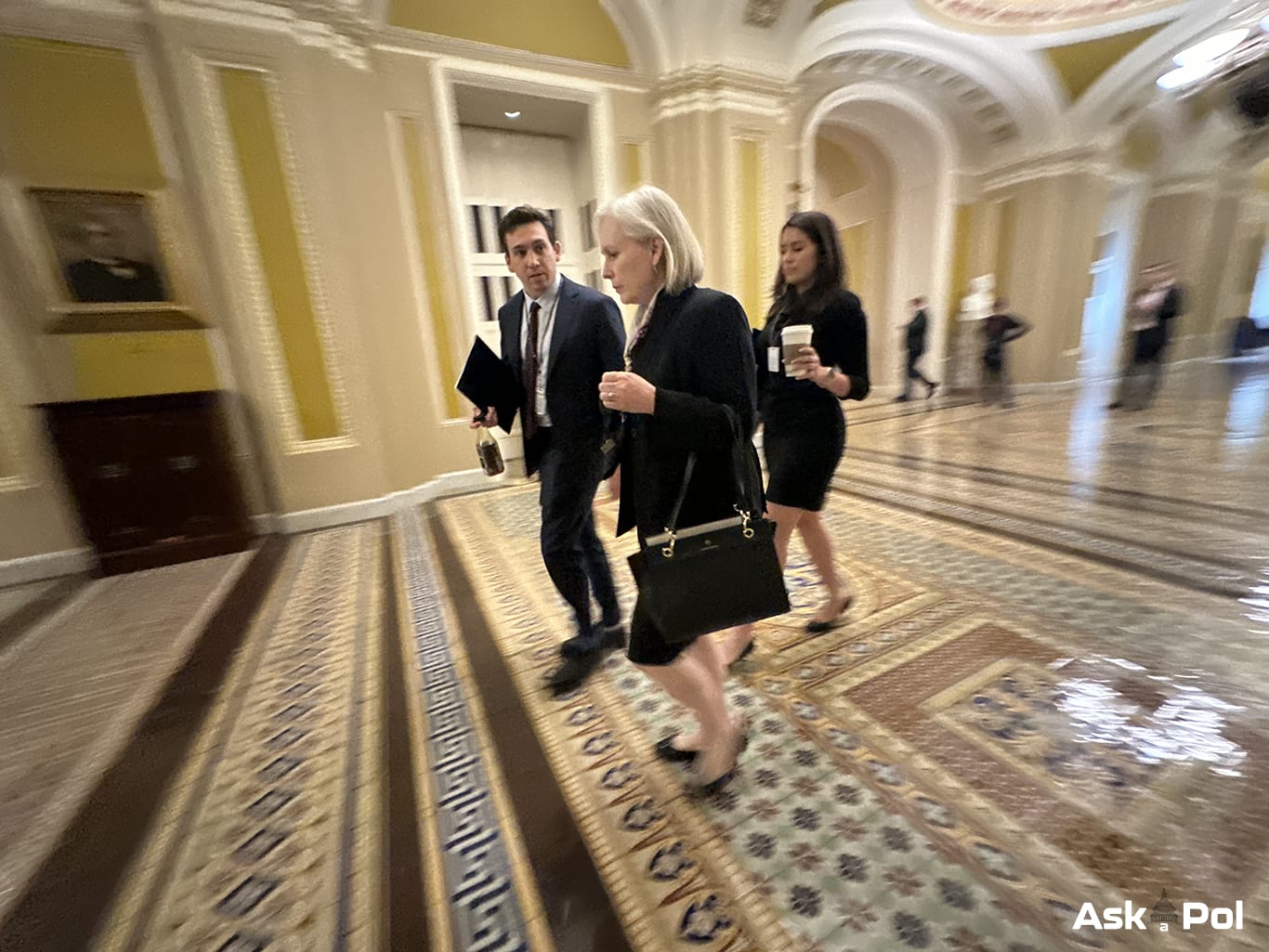 A female politician in business suit walks in US Capitol accompanied by 2 aides. Photo © Matt Laslo www.askapol.com A female politician in business suit walks in US Capitol accompanied by 2 aides. Photo © Matt Laslo www.askapol.com
