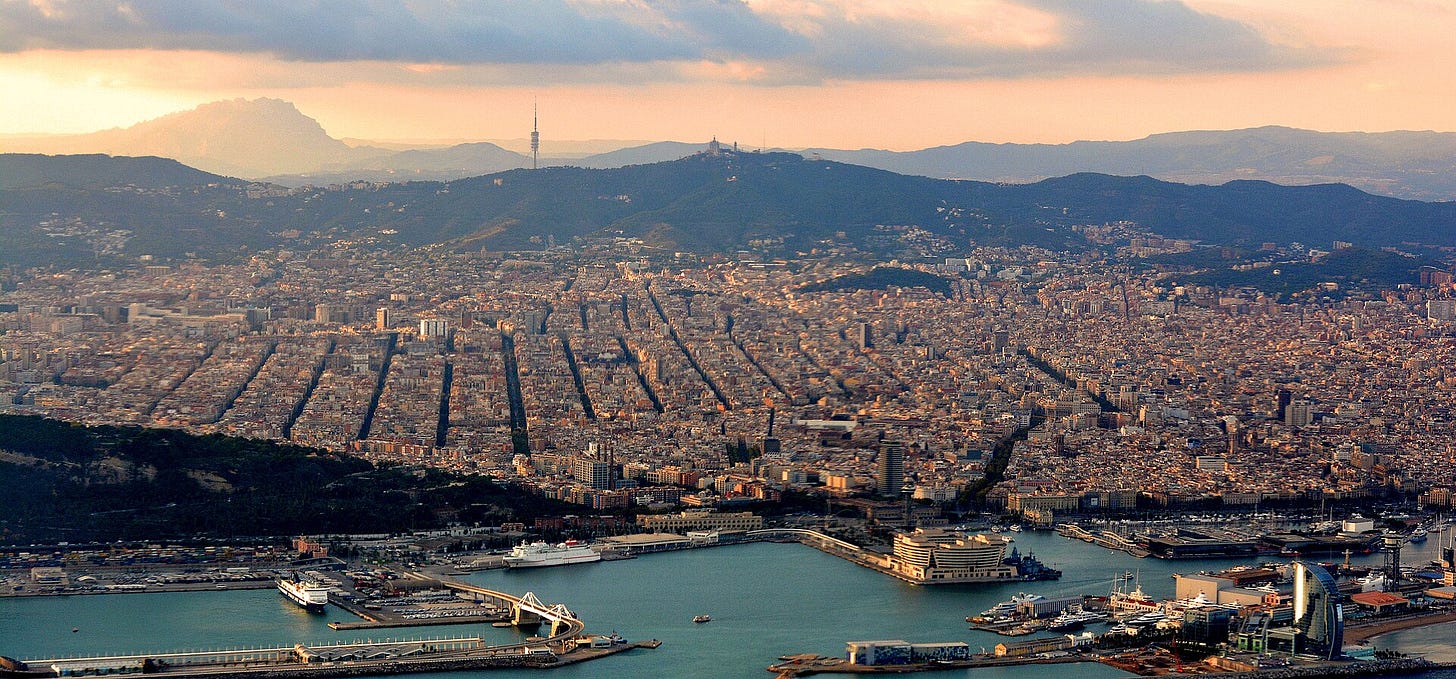 Evening aerial view over Barcelona, with the port in the foreground and Montserrat mountain visible in the distance. Evening aerial view over Barcelona, with the port in the foreground and Montserrat mountain visible in the distance.