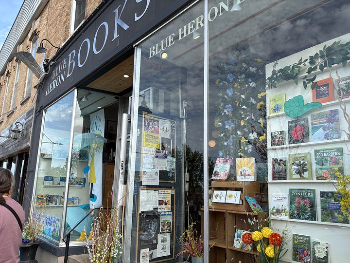 In these photos, we see the storefront display of Blue Heron Books in Uxbridge, Ontario, as well as a photo of Dinah's haul: two books, a table game called "Not Today, Murder" and a lapel pin for the Thursday Murder Club, Dinah's favourite mystery novel ever. These photos were take on an excursion during Rekindle Creativity Women's Writing Retreat in May 2026, which Dinah Laprairie cohosts with Liisa Kovala.