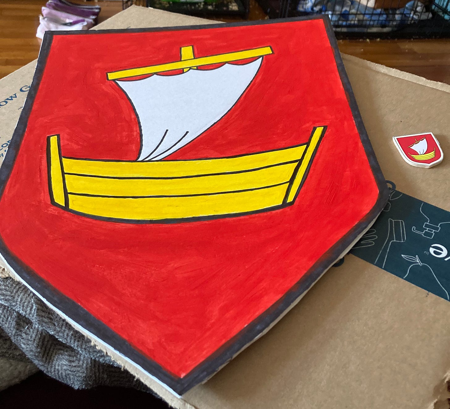 A very large shield with the image of a boat on it next to a tiny version of the same shield.