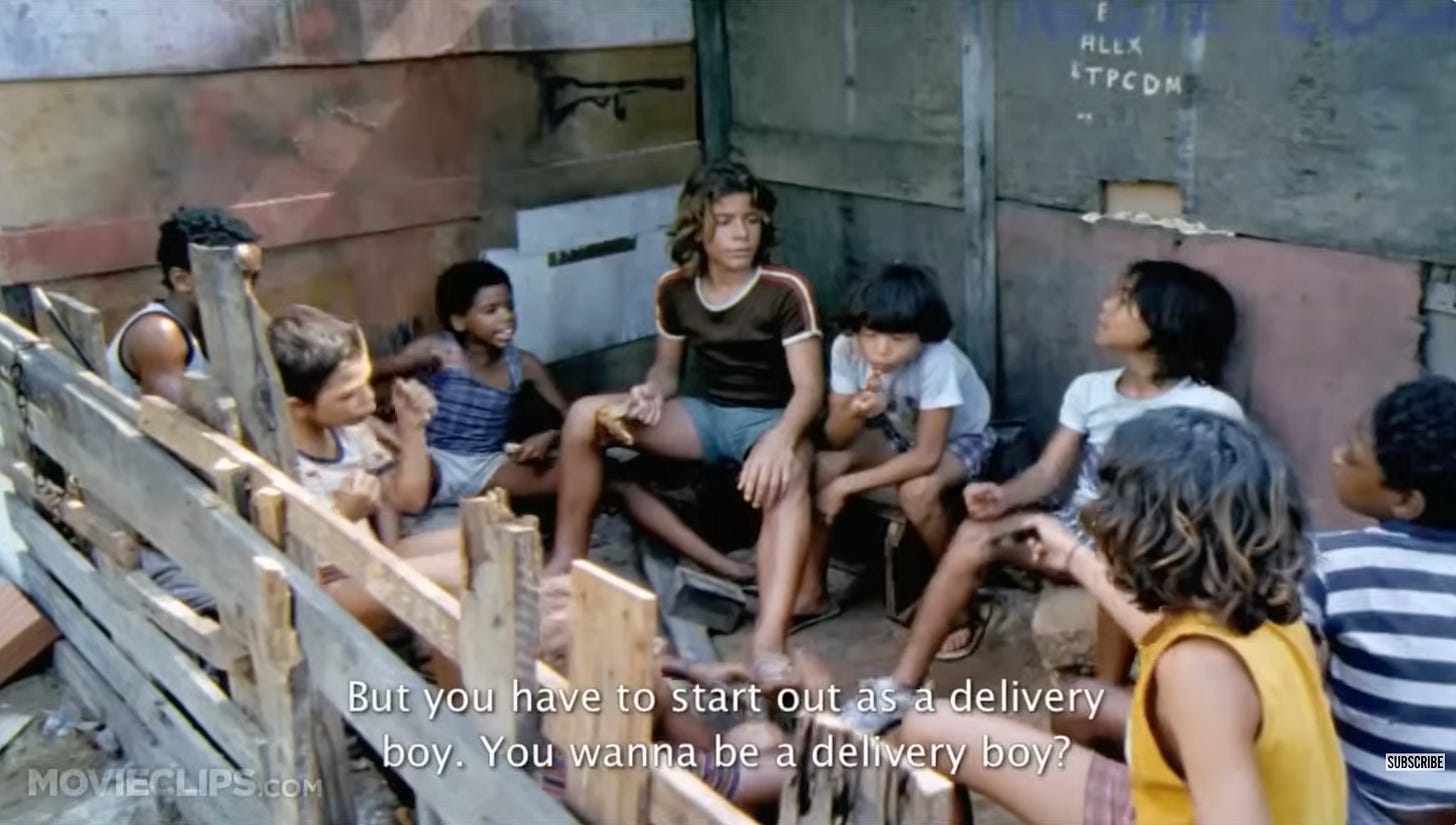 A group of children gathered in what looks like it could be a barn stall, but is an outdoor yard in a Favela, with the caption "but you have to start as a delivery boy."