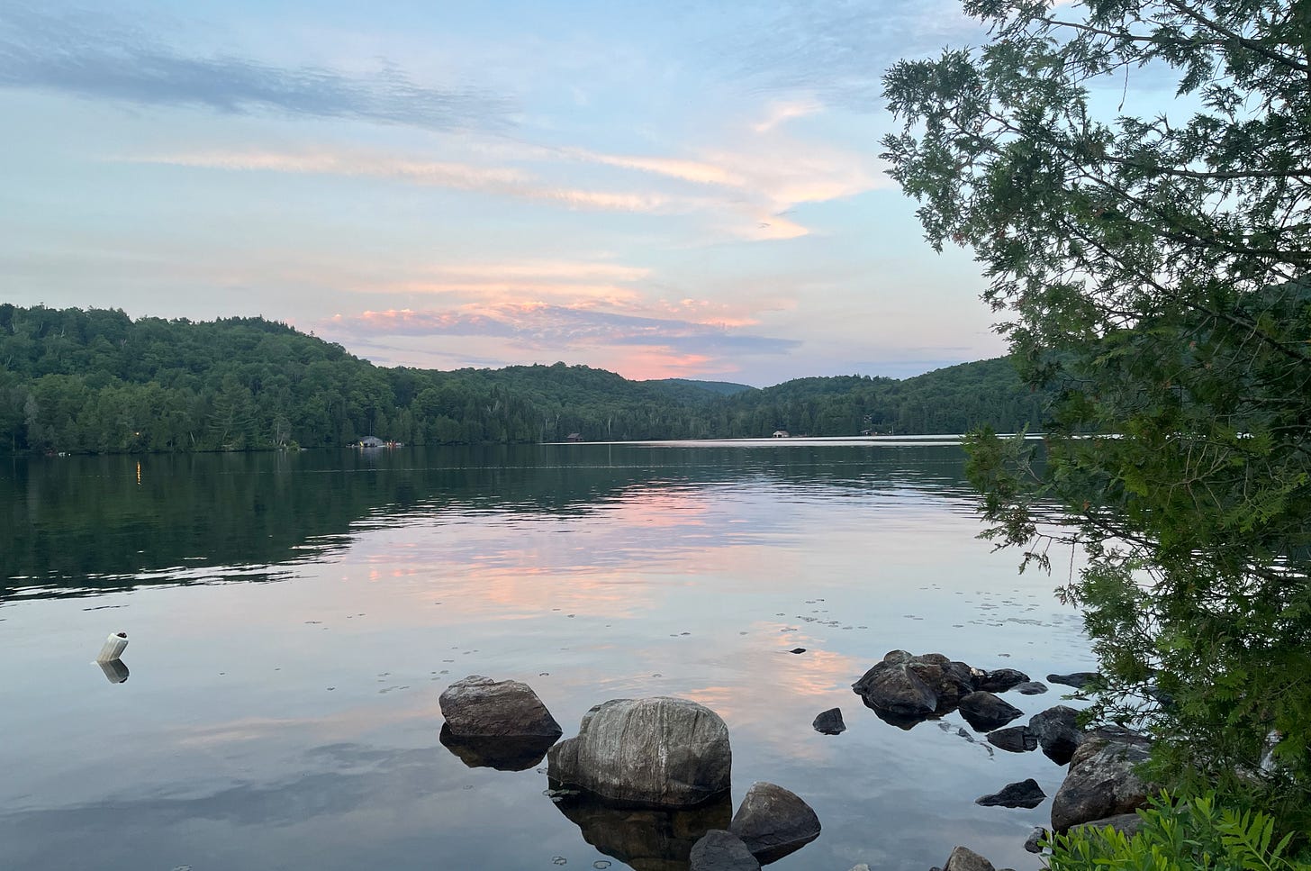 A large lake with pink skies reflected in its still surface.