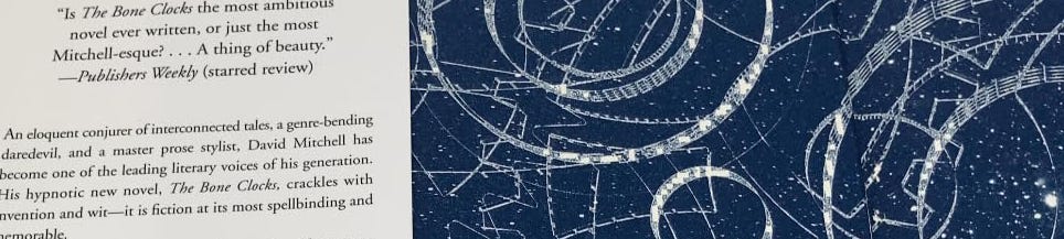 A thin horizontal strip from the open front cover of the hardcover edition of The Bone Clocks is shown, with a snippet of text from the jacket and a section of art that looks like a classical star chart drawn in white on a dark blue background. The text says: " 'Is The Bone Clocks the most ambitious novel ever written, or just the most Mitchell-esque? ... A thing of beauty.' --Publishers Weekly (starred review). An eloquent conjurer of interconnected tales, a genre-bending daredevil, and a master prose stylist, David Mitchell has become one of the leading literary voices of his generation. His hypnotic new nove, The Bone Clocks, crackles with invention and wit--it is fiction at its most spellbinding and memorable." A thin horizontal strip from the open front cover of the hardcover edition of The Bone Clocks is shown, with a snippet of text from the jacket and a section of art that looks like a classical star chart drawn in white on a dark blue background. The text says: " 'Is The Bone Clocks the most ambitious novel ever written, or just the most Mitchell-esque? ... A thing of beauty.' --Publishers Weekly (starred review). An eloquent conjurer of interconnected tales, a genre-bending daredevil, and a master prose stylist, David Mitchell has become one of the leading literary voices of his generation. His hypnotic new nove, The Bone Clocks, crackles with invention and wit--it is fiction at its most spellbinding and memorable."