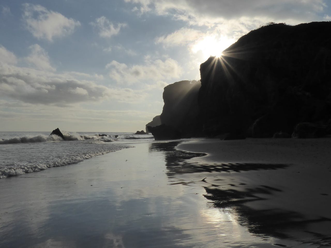 Reflection of a cliff on wet sand