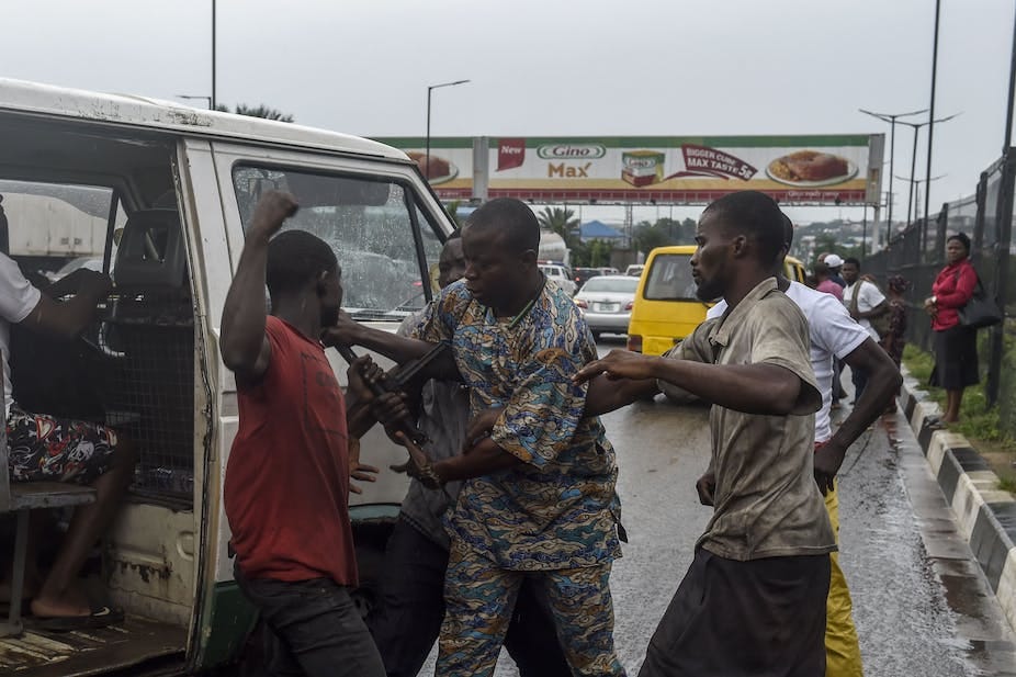 Two men fighting beside a minibus