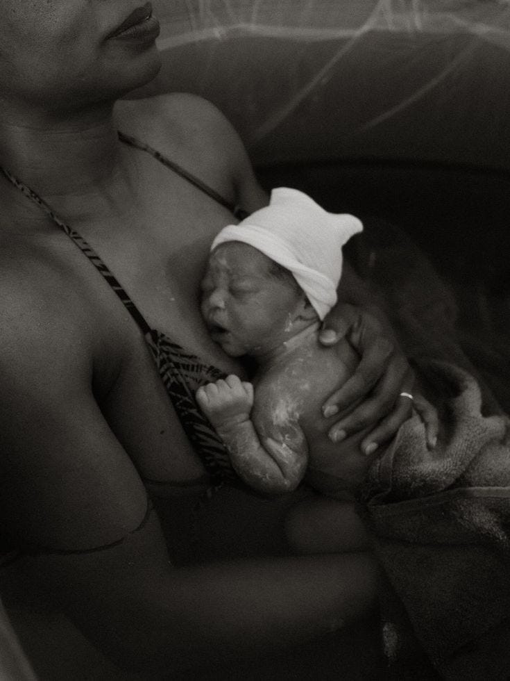 This may contain: a black and white photo of a woman holding a baby in a bathtub with her head wrapped up This may contain: a black and white photo of a woman holding a baby in a bathtub with her head wrapped up