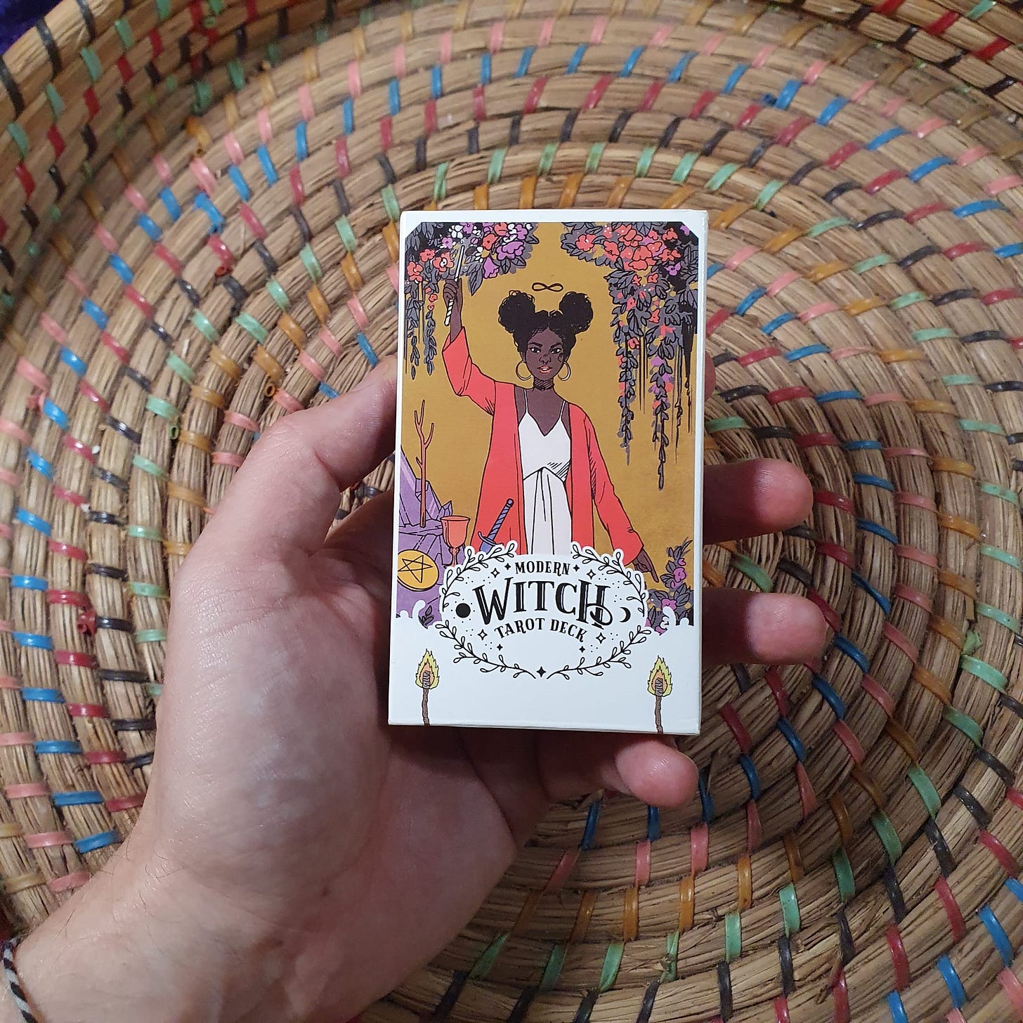 A picture of the Modern Witch Tarot deck being held in Finbarre's hand