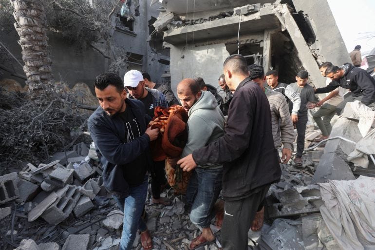 Palestinians carry the body of a person recovered from the site of an Israeli strike on a house