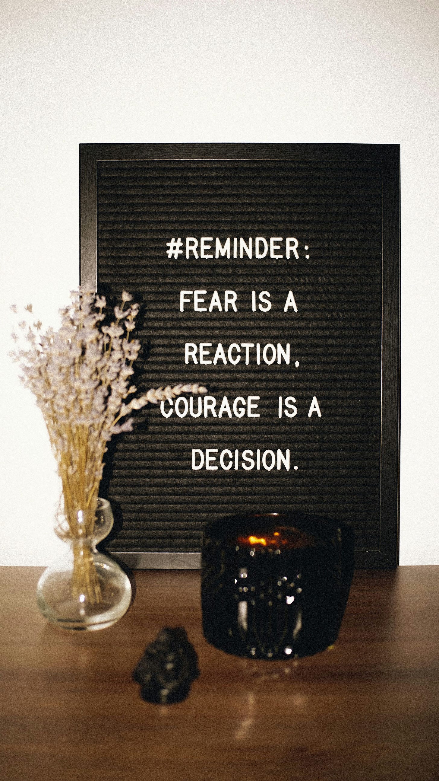 black board shows a message that says: Reminder: Fear is a reaction and courage is a decision.