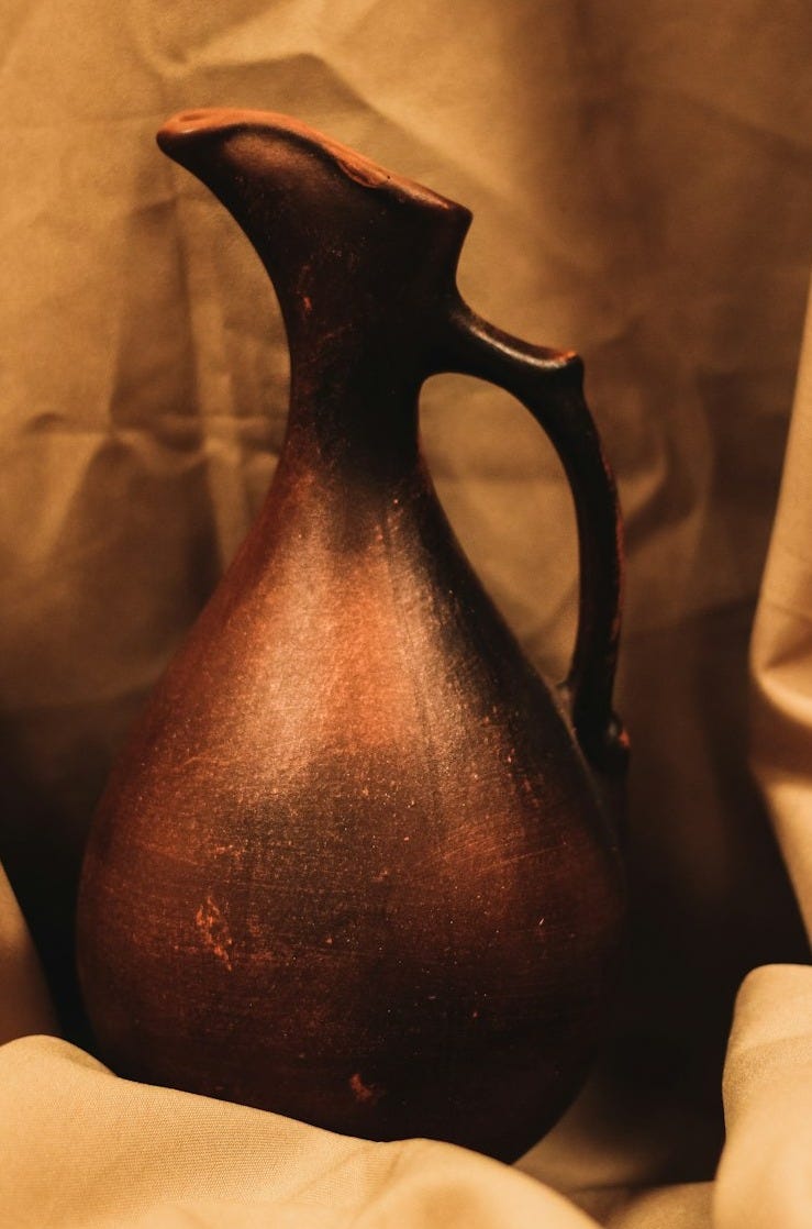 Earthenware jug with handle on draped fabric