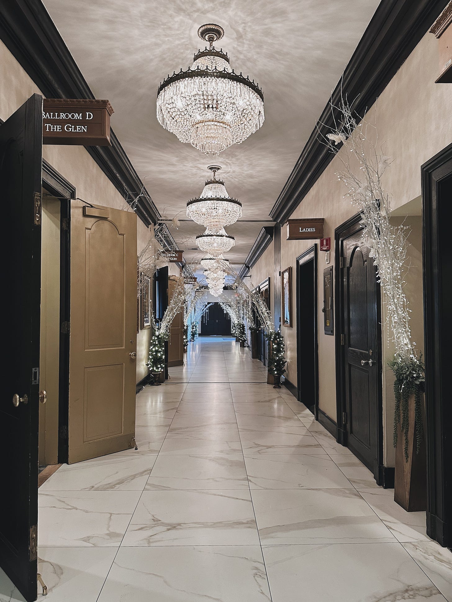 The Drake Oak Brook's hallway filled with holiday decor, featuring crystal chandeliers and garlands.