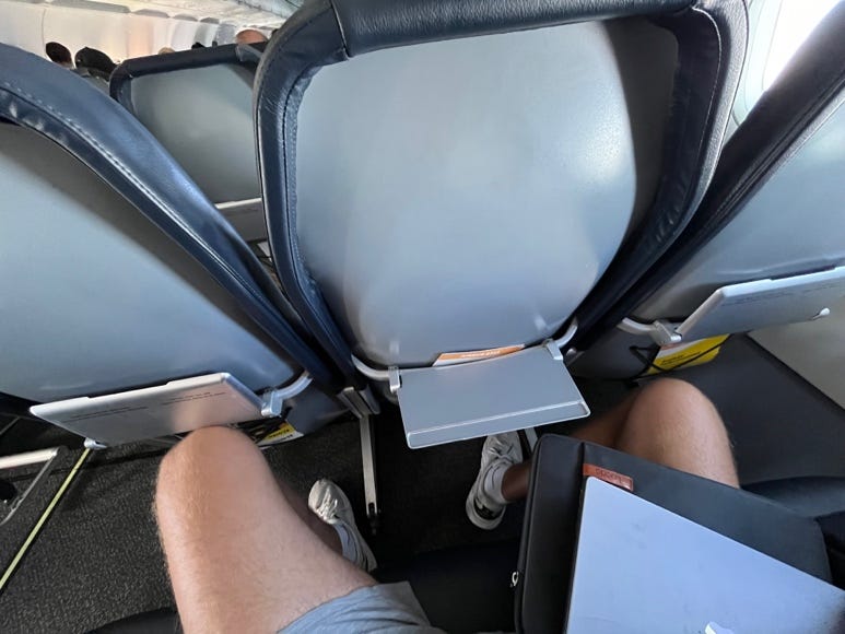 A person's legs in a row of seats

Description automatically generated