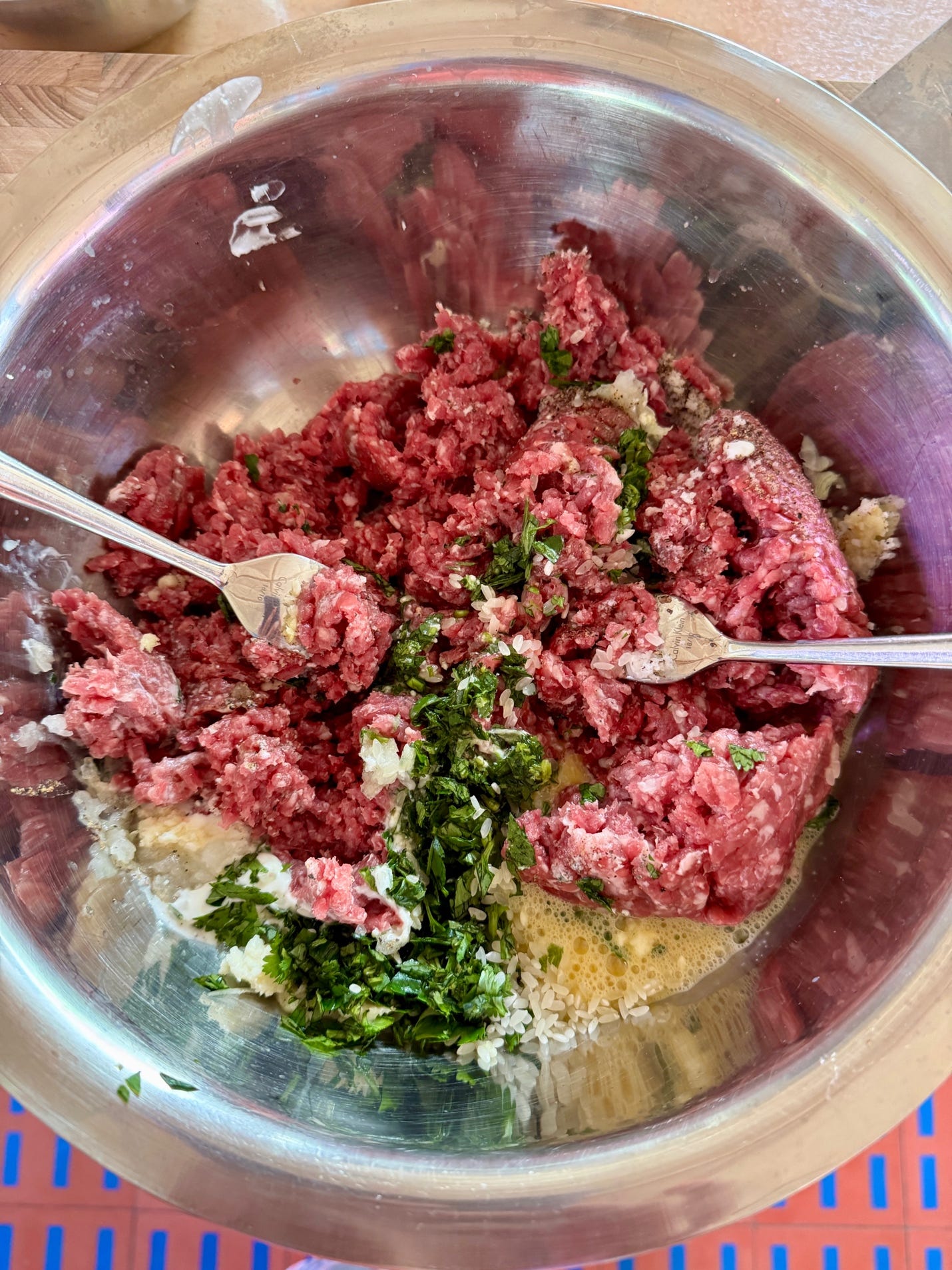 Using a fork to mix the ground beef with the ingredients for caldo de albóndigas meatballs.