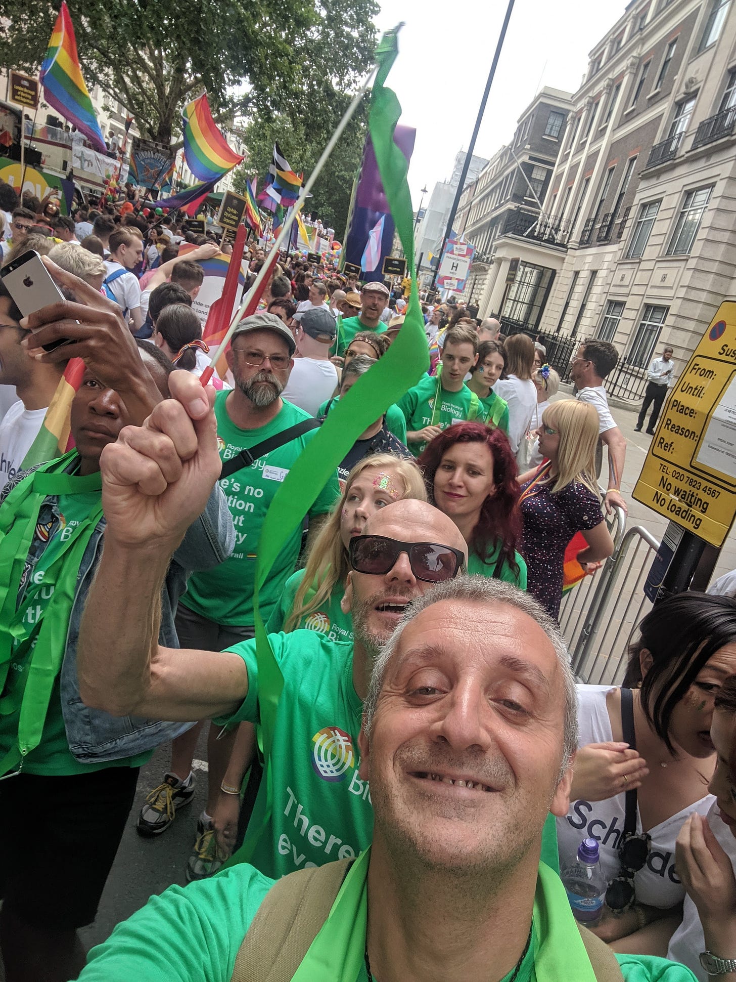 A selfie of a group of people, wearing green t-shirts at waving rainbow flags, marching with the Royal Society of Biology at London Pride 2019 A selfie of a group of people, wearing green t-shirts at waving rainbow flags, marching with the Royal Society of Biology at London Pride 2019