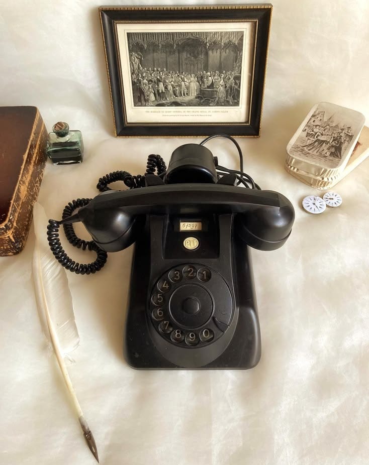 This may contain: an old fashioned telephone sitting on top of a bed next to a feather quill