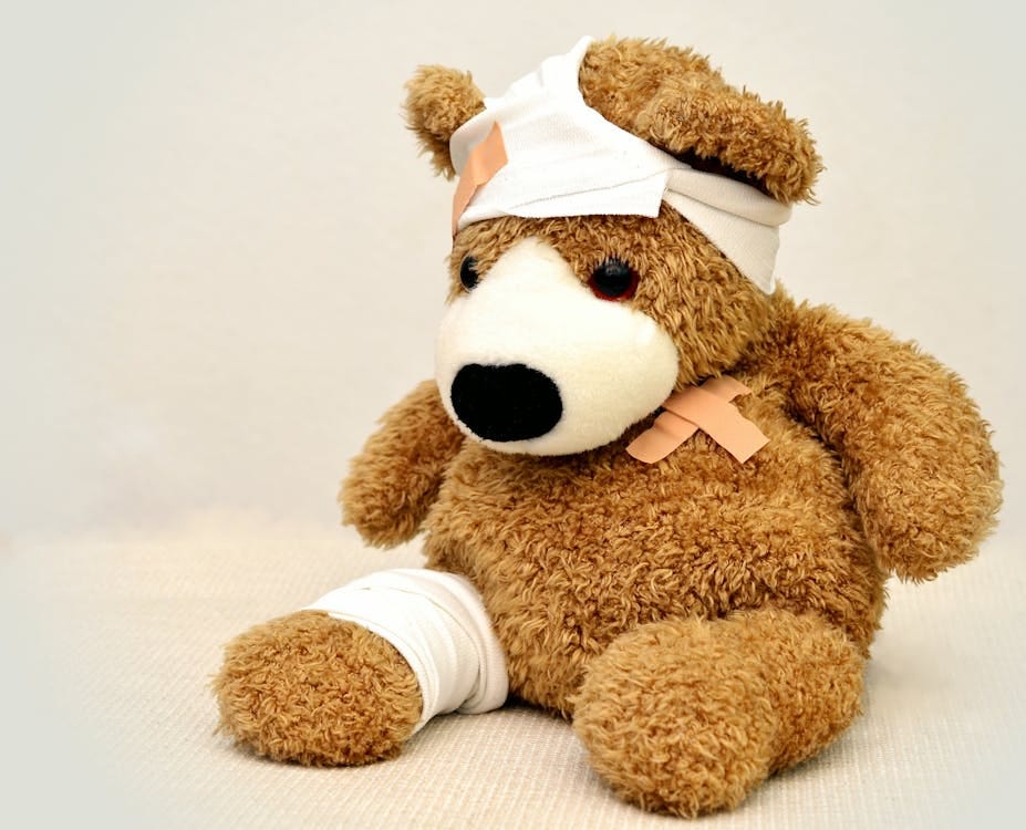 Free A brown teddy bear with bandages, depicting a playful take on injury recovery in a minimalist setting. Stock Photo