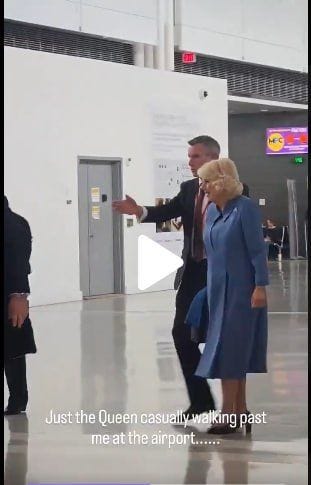 Un hombre con traje y una mujer con vestido azul caminan juntos por el aeropuerto.