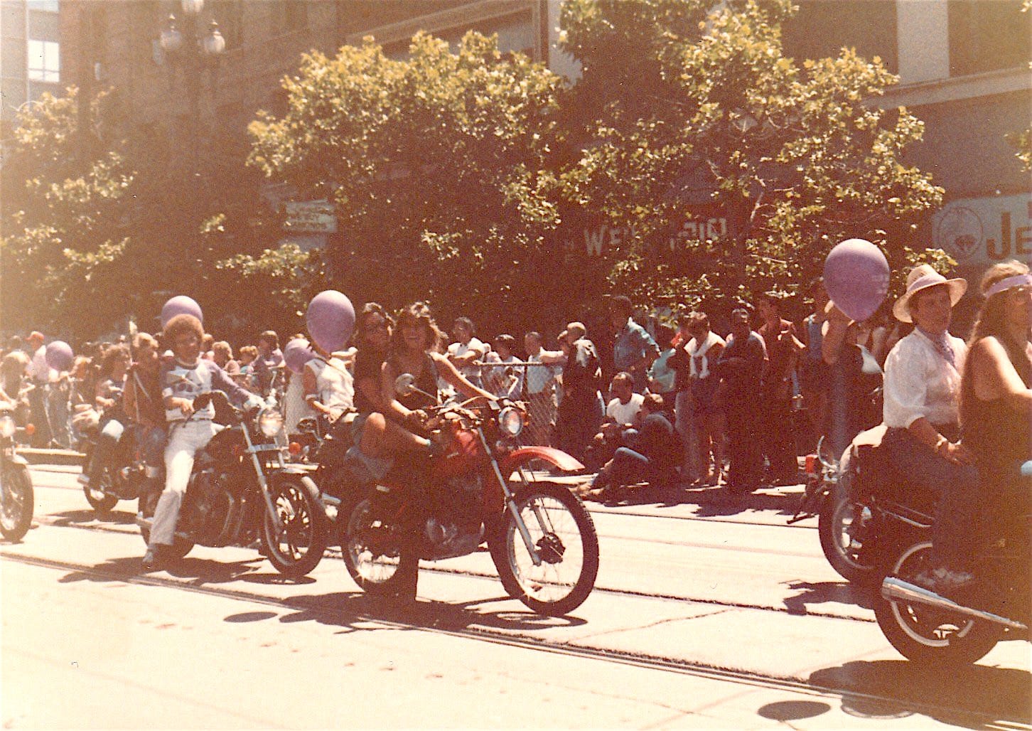 Women ride motorcycles decorated with balloons along a parade route. Women ride motorcycles decorated with balloons along a parade route.
